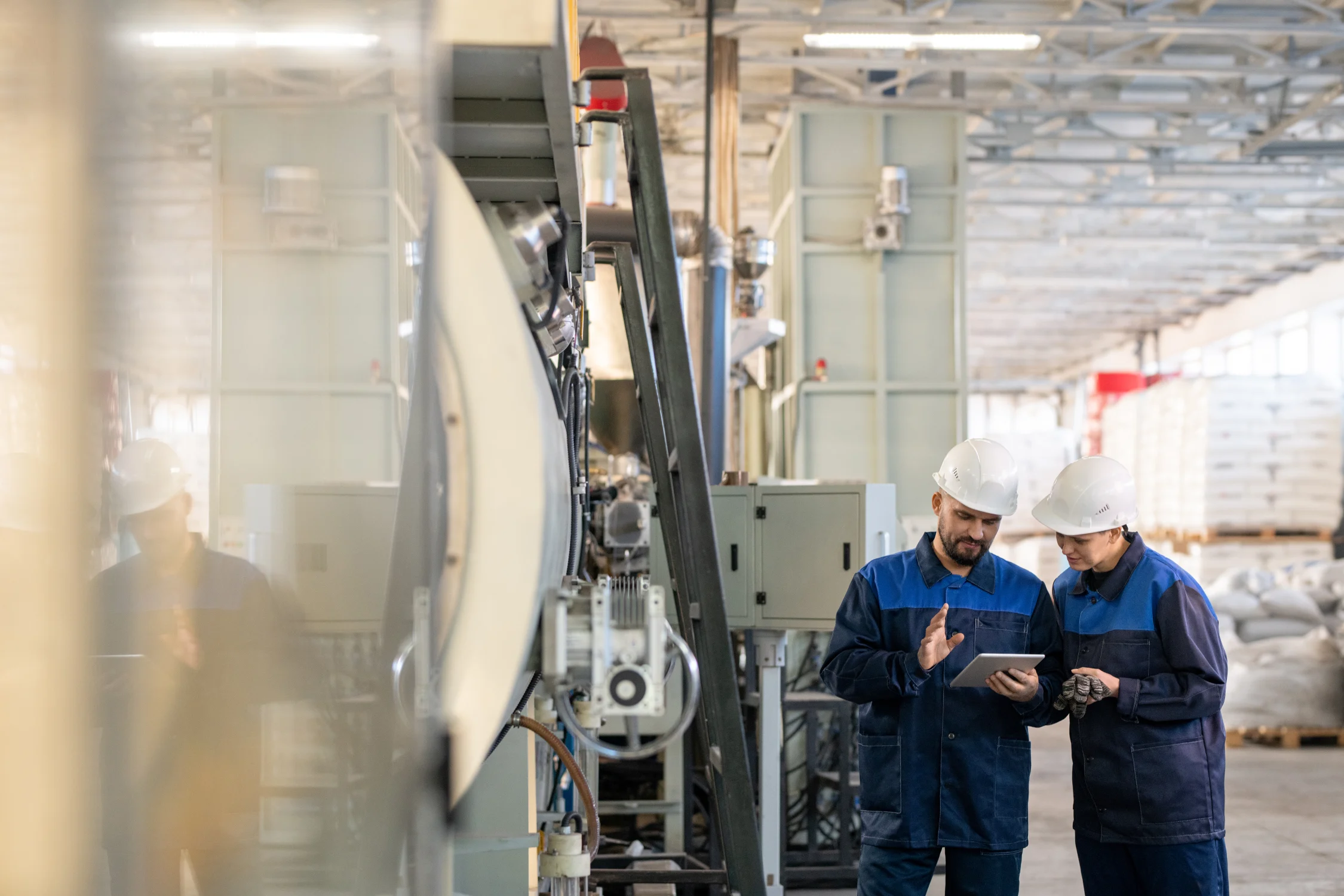 Two engineers discussing technical data and machine details in industrial workshop